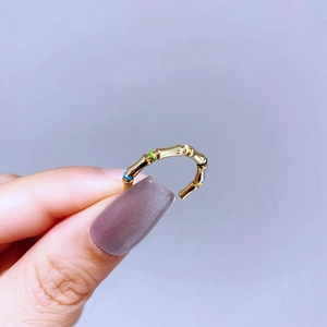 Detail of adjustable gold bamboo ring featuring colorful enamel accents and polished finish