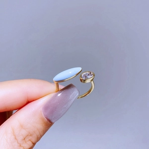 Detailed shot of a gold open ring with light blue marquise stone and oval zircon inlay