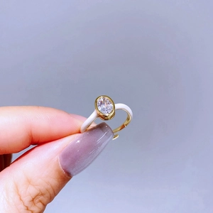 Detail of a gold adjustable ring with white enamel coating and oval zircon stone