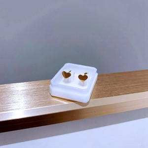 Makroaufnahme goldener Herz-Ohrstecker aus Titan in einer weißen Schmuckschatulle