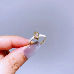 Detail view of gold adjustable ring with white enamel and marquise-cut zircon stone