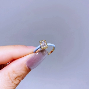 Macro detail of gold ring with rectangular crystal and light blue enamel finish