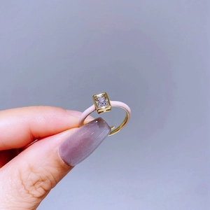 Macro shot of gold ring with pink enamel detail and rectangular zircon featuring H-shaped base