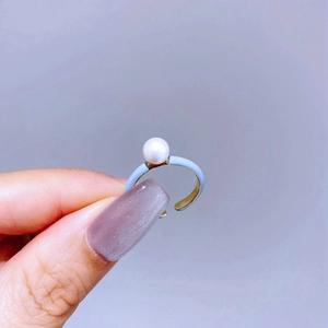 Close-up of elegant gold and light blue enamel adjustable ring with a white pearl