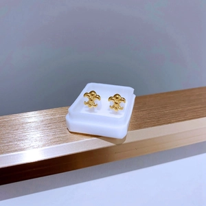 Nahaufnahme der vergoldeten Fleur-de-Lis-Ohrstecker aus Titanstahl auf einem Ständer