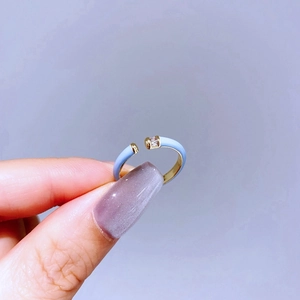Detail of light blue enamel ring with a rectangular zircon on a golden metal band
