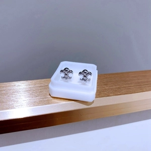 Nahaufnahme polierter Fleur-de-Lis Titanstahl Ohrstecker auf einem Displayständer