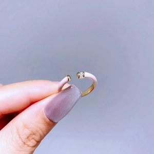 Detail of gold-plated open ring with pink enamel coating and sparkling zircon stone