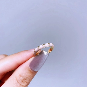 Detailed shot of an adjustable pink enamel ring with golden star patterns on fingers
