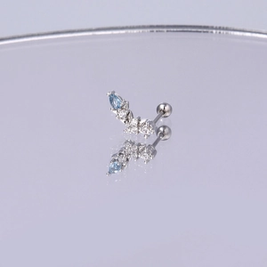Detail von blauem Zirkon-Ohrstecker mit Schraubverschluss auf violettem Spiegel