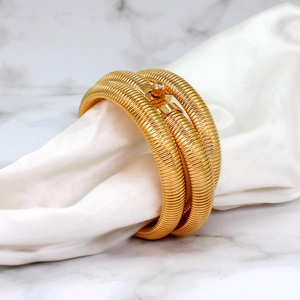 Detailed view of golden Tubogas spiral bracelet featuring white cubic zirconia on white silk