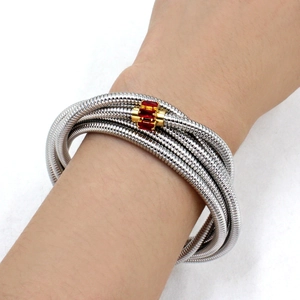 Close-up of a multi-layer silver coil bracelet with red rectangular zircon inlays