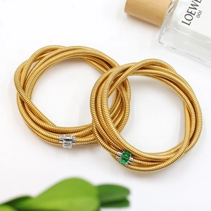Detail of gold Tubogas snake chain bracelets with white and emerald green zircon stones