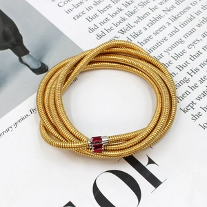 Detailed macro view of gold multi-layer snake chain bracelet with red square gemstones