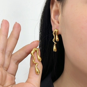 Close-up of irregular gold molten earrings showing the metallic mirror texture on ear