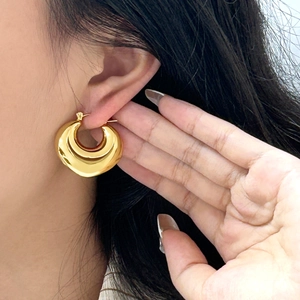 Nahaufnahme eines großen klobigen Goldohrrings mit hochglanzpoliertem Finish am Modell