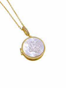 Macro shot of 18K gold plated necklace with angel relief on white mother of pearl