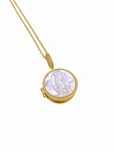 Macro detail of golden Guadalupe locket necklace with white mother of pearl inlay