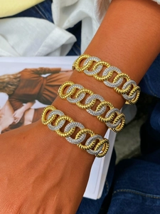Dettaglio di bracciali a catena bicolore oro e argento con zirconi al polso di un modello