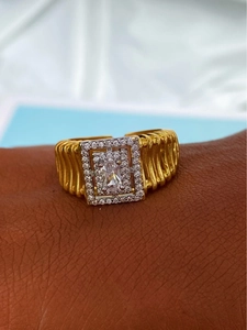 Détail de la bague rectangulaire dorée en zircon avec texture plissée et cristaux pavés