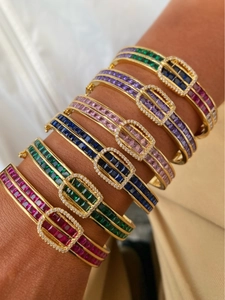 Détail de bracelets boucle fer à cheval avec zircons colorés et placage en or 18 carats