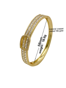Détail d'un bracelet doré 18k avec boucle en fer à cheval et zircons en forme de T