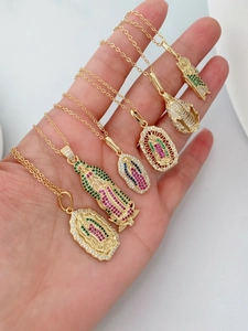 Detalle de collares dorados con colgantes de la Virgen María incrustados de circonitas de colores