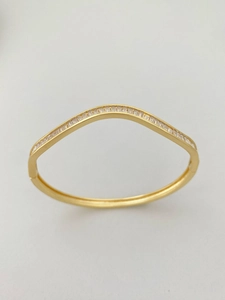 Makroaufnahme von goldenem Wellenarmband mit rechteckigen Zirkoniasteinen und Politur