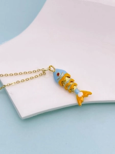 Macro detail of a colorful enamel fish pendant with blue scales and gold hollow accents