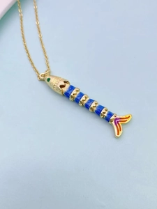 Macro shot of colorful fish pendant with blue enamel sections and gold metal frame