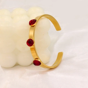 Minimalist gold titanium steel open bangle featuring three oval red zircon stone accents