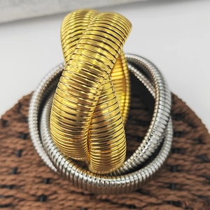 Makro-Detail von gold- und silbernen Schlangenarmbändern auf einer gewebten Matte