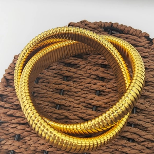 Makro-Detail von goldenem Tubogas-Schlangenarmband mit flexibler Spiralwebstruktur