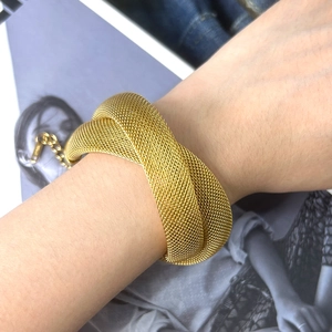 Bracciale rigido dorato a maglia intrecciata dal design incrociato con pendente