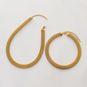 Dettaglio del set collana e bracciale in maglia dorata con chiusura a moschettone