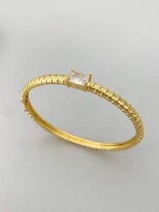 Dettaglio macro del bracciale placcato oro 18K con trama a spirale e zircone rettangolare