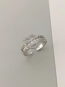 Gros plan d'une bague argentée avec motif cœur évidé et cristaux brillants sertis