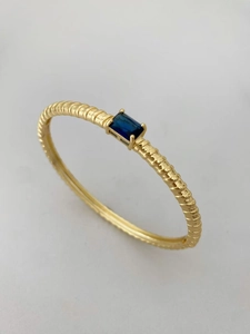 Dettaglio del bracciale placcato oro con trama a coste e zircone blu rettangolare incastonato
