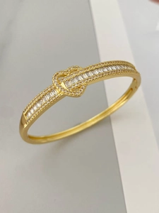 Détail du bracelet plaqué or 18 carats avec zircons pavés au design boucle de ceinture entrelacée