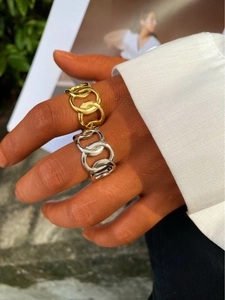 Primer plano de anillos de cadena gruesa en oro y plata usados por una modelo