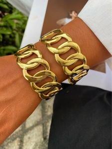 Primer plano de pulseras anchas de cadena dorada lucidas con un estilo elegante