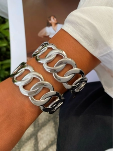 Primer plano de dos pulseras de cadena cubana plateadas en la muñeca con camisa blanca