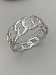 Primer plano detallado de un anillo de cadena cubana en metal plateado pulido