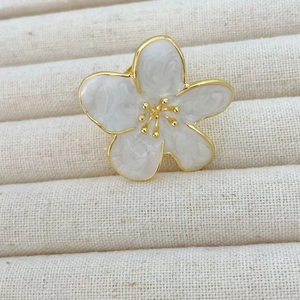 Macro shot of camellia flower ring with ivory petals, gold edges, and marble texture