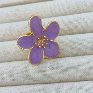 Detail of a purple camellia flower ring with golden edges on a jewelry tray