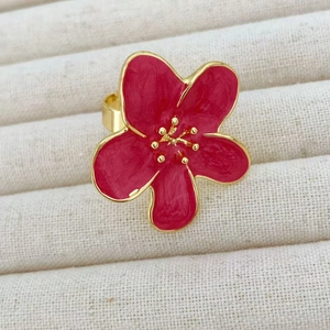 Macro detail of red enamel camellia flower ring with polished golden metal finish