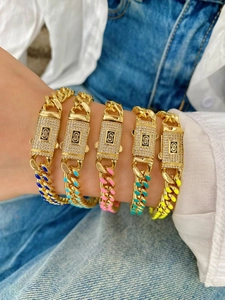 Dettaglio di bracciali a catena cubana dorati con ciondoli S in strass e smalto colorato