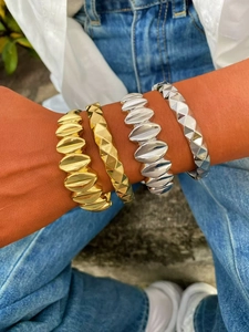 Detalle de brazaletes en oro y plata con texturas acanaladas y acabados facetados