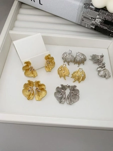 Macro shot of gold and silver floral earrings with zircons in a white jewelry box