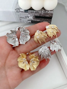 Close-up of sparkling angel wing stud earrings in gold and silver with cubic zirconia